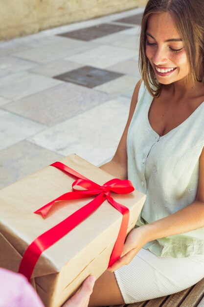 Nahaufnahme einer glücklichen jungen Frau, die Geschenk empfängt