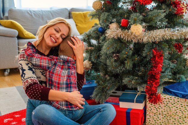 Nahaufnahme einer glücklichen Mutter, die ihren Sohn umarmt, Weihnachtsstimmung in einem gemütlichen Haus