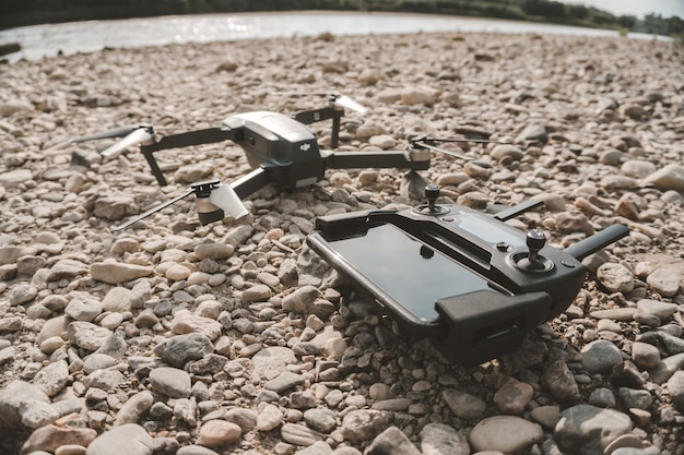 Nahaufnahme einer High-Tech-Drohne und ihres Fernbedienungsgeräts auf grauen Kieselsteinen