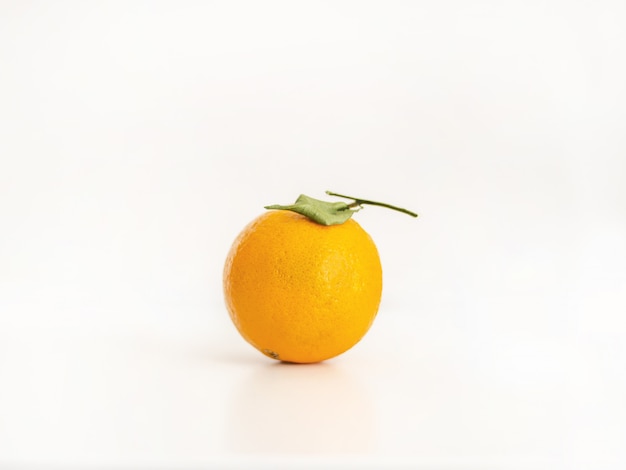 Nahaufnahme einer isolierten ganzen Orange mit einem Blatt auf einem hellen hellrosa Hintergrund