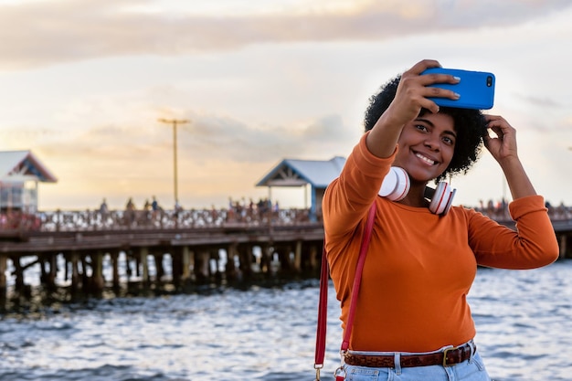 Nahaufnahme einer jungen attraktiven Dame mit Kopfhörern, die ein Selfie macht