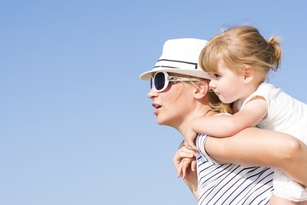 Nahaufnahme einer kaukasischen Mutter, die ihrer Tochter bei Tageslicht eine Huckepackfahrt gibt