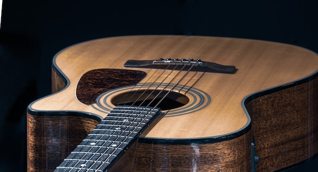 Kostenloses Foto nahaufnahme einer klassischen akustikgitarre auf schwarzem hintergrund.