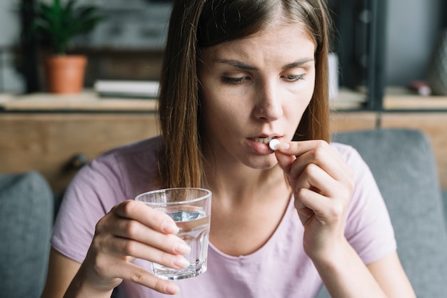 Nahaufnahme einer kranken jungen Frau, die Medizin einnimmt