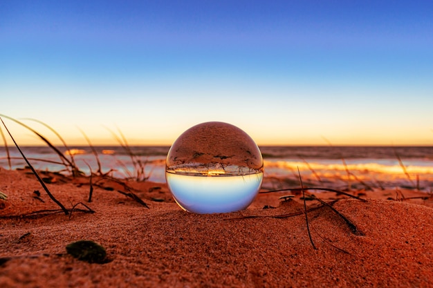 Kostenloses Foto nahaufnahme einer kristallkugel am strand mit der umgebung, die darauf reflektiert