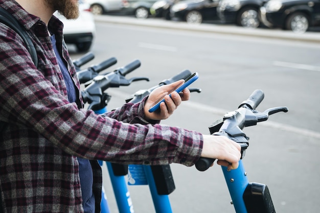 Kostenloses Foto nahaufnahme einer männerhand, die eine mobile app zum mieten eines elektrorollers nutzt