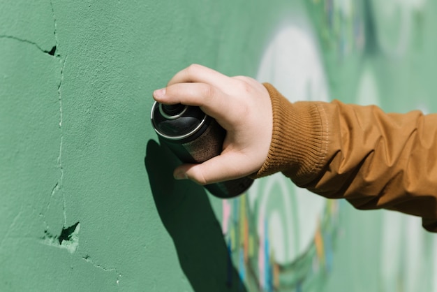 Nahaufnahme einer menschlichen Hand, die Graffiti mit Aerosoldose macht