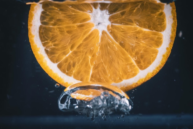 Nahaufnahme einer Orangenscheibe, die im Wasser spritzt