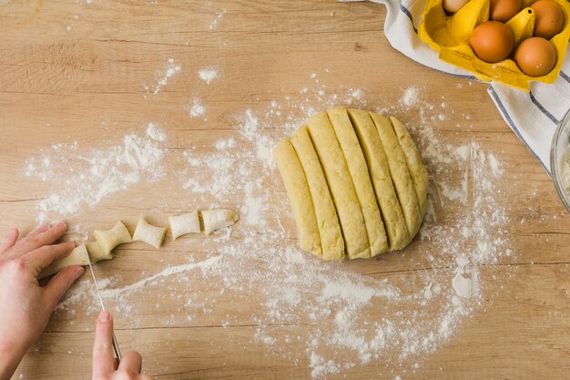 Nahaufnahme einer Person, die den Teig für das Zubereiten der frischen italienischen Teigwaren Gnocchi schneidet