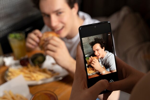 Nahaufnahme einer Person, die ein Foto von Lebensmitteln macht