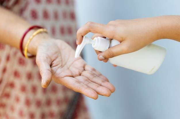 Nahaufnahme einer Person, die eine Flüssigseife auf die Hand einer Frau gießt