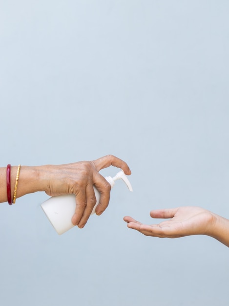 Nahaufnahme einer Person, die einer anderen Person Flüssigseife in die Hand gießt