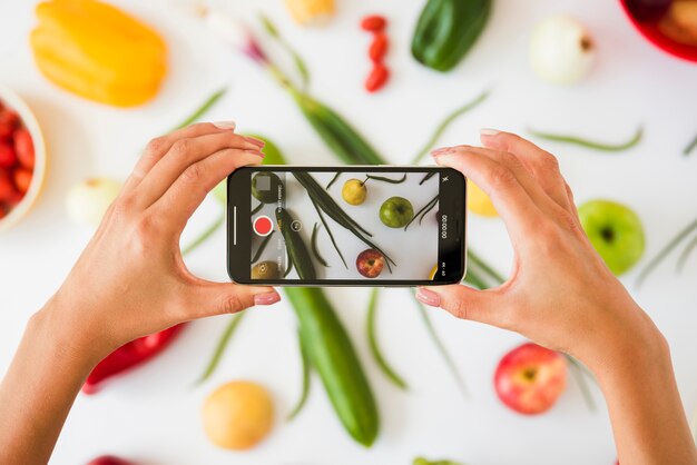 Nahaufnahme einer Person, die Foto des Gemüses auf weißem Hintergrund macht