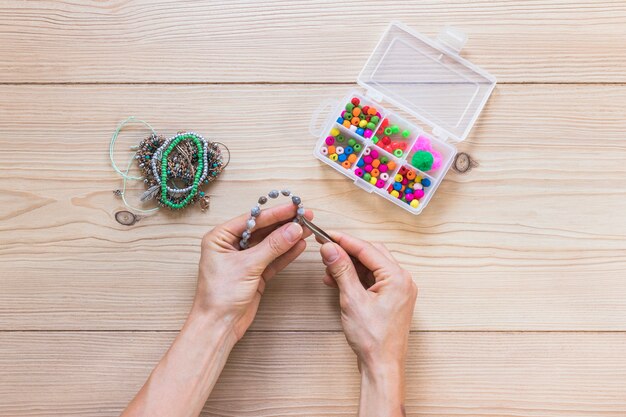 Nahaufnahme einer Person, die handgemachtes Armband mit Pinzette macht