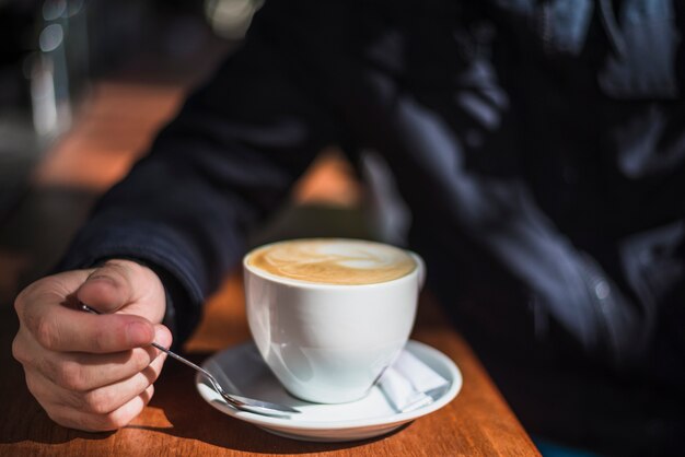 Nahaufnahme einer Person mit Cup heißem Espressokaffee auf Tabelle