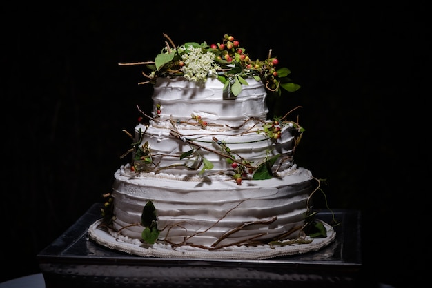 Kostenloses Foto nahaufnahme einer rustikalen hochzeitstorte mit grünen blättern, zweigen und kleinen runden beeren