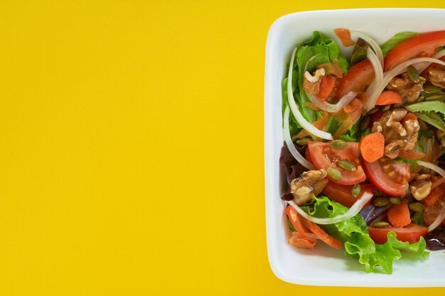 Nahaufnahme einer Salatplatte auf gelbem Hintergrund. Gesundes vegetarisches Essen. Platz für Text