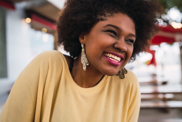 Nahaufnahme einer schönen afroamerikanischen lateinamerikanischen Frau, die lächelt und schöne Zeit am Kaffeehaus verbringt.