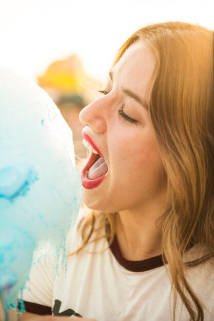 Nahaufnahme einer schönen Frau, die blaue Zuckerwatte isst