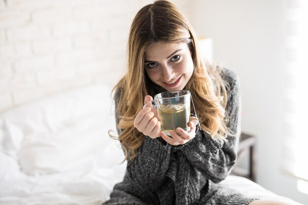 Nahaufnahme einer schönen jungen Frau, die gemütlich aussieht und eine Tasse Tee genießt