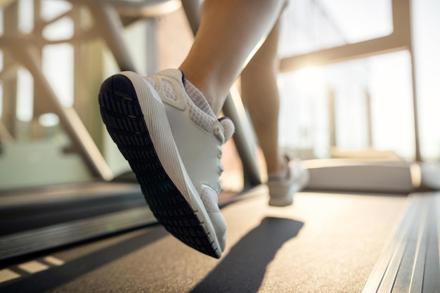 Nahaufnahme einer Sportlerin, die auf der Laufstrecke im Fitnessstudio joggt