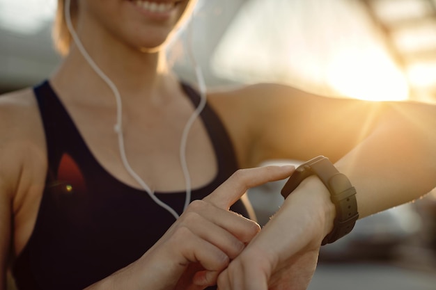 Nahaufnahme einer sportlichen Frau mit Fitness-Tracker bei Sonnenuntergang