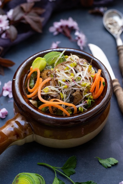 Nahaufnahme einer veganen Mahlzeit mit Pilzen, Zwiebeln, Karotten und Lauch