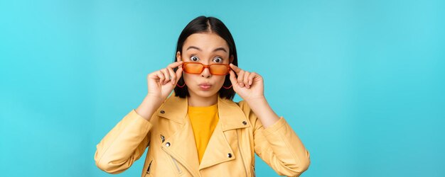 Nahaufnahme eines asiatischen Mädchens mit Sonnenbrille, das glücklich und überrascht auf dem Gesicht steht