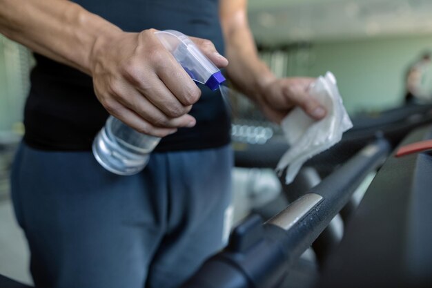 Nahaufnahme eines Athleten, der die Laufbahn in einem Fitnessstudio desinfiziert