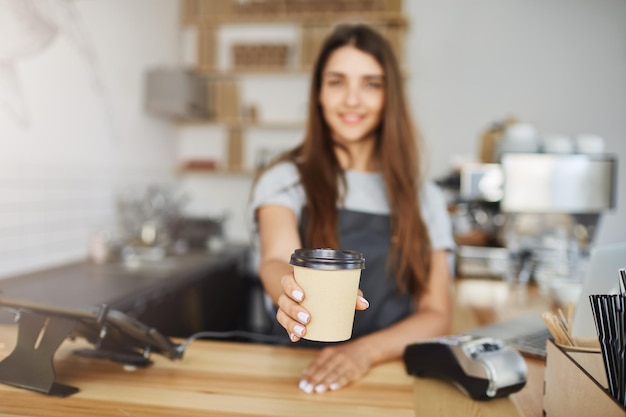 Nahaufnahme eines Baristas, der einem Kunden eine Tasse Kaffee zum Mitnehmen serviert