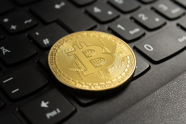 Nahaufnahme eines Bitcoin auf einer schwarzen Computertastatur