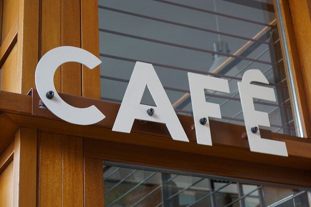 Nahaufnahme eines Cafe-Schildes auf einem Holzbalken eines Geschäfts fixiert