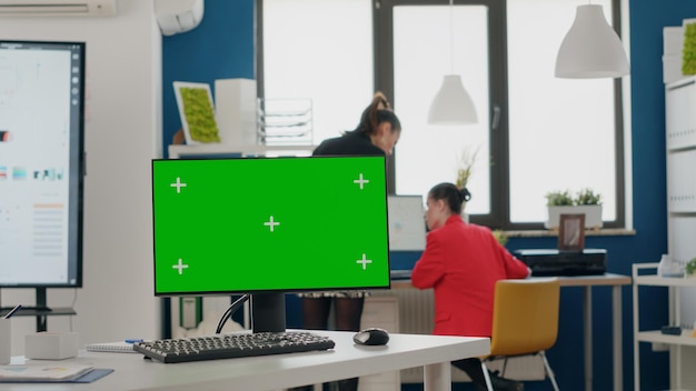 Nahaufnahme eines computers mit leerem grünen bildschirm im geschäftsbüro. chroma-schlüssel mit isoliertem hintergrund und mock-up-vorlage auf dem monitordisplay. moderne chroma-key-anwendung mit kopierbereich