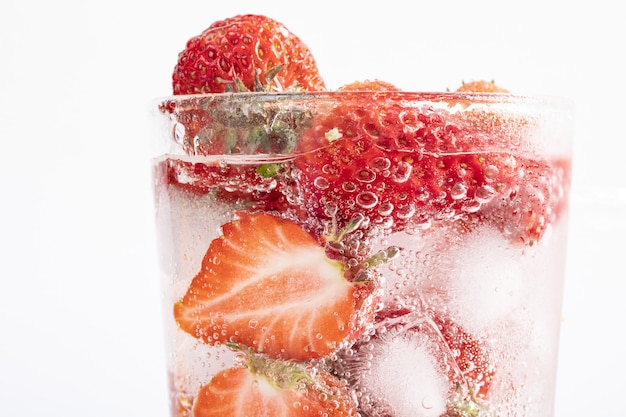 Nahaufnahme eines erfrischenden Getränks mit einer Scheibe Erdbeeren und Eiswürfeln