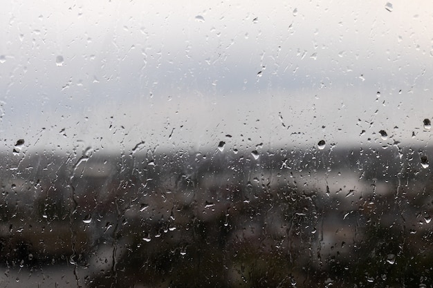 Nahaufnahme eines Fensters an einem regnerischen düsteren Tag, Regentropfen, die das Fenster hinunter rollen