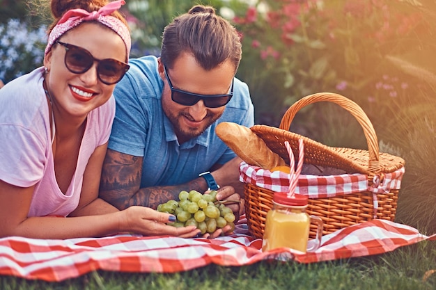 Nahaufnahme eines glücklichen Paares mittleren Alters während eines romantischen Dates im Freien, das ein Picknick genießt, während es auf einer Decke im Park liegt.