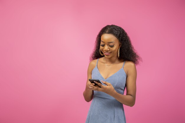 Nahaufnahme eines hübschen afroamerikanischen Mädchens in einer aufregenden Stimmung, die ihr Telefon hält