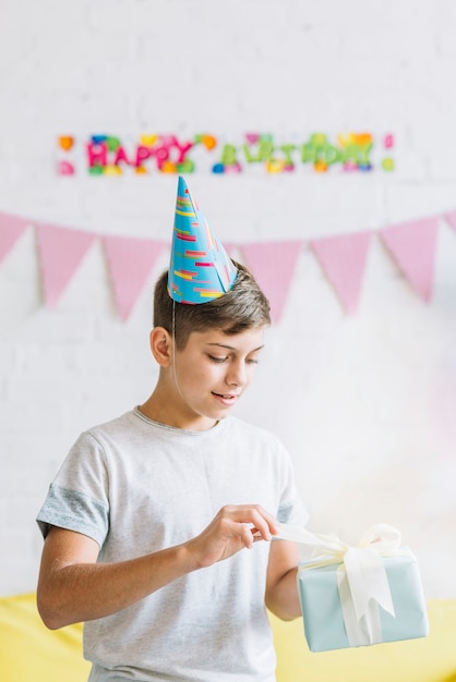 Nahaufnahme eines Jungen, der Geburtstagsgeschenk auspackt