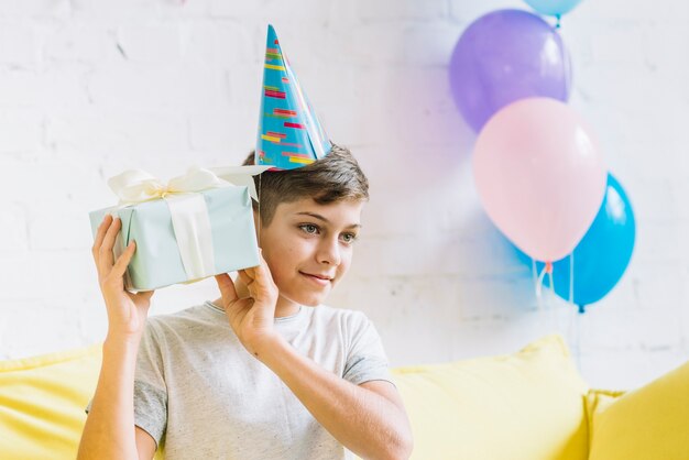 Nahaufnahme eines Jungen, der Geburtstagsgeschenk rüttelt