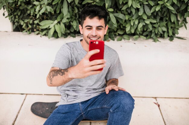 Nahaufnahme eines Jungen, der selfie mit seinem roten Handy nimmt