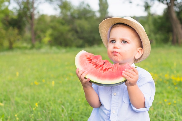 Nahaufnahme eines Jungen, der Wassermelonenscheibe im Park isst