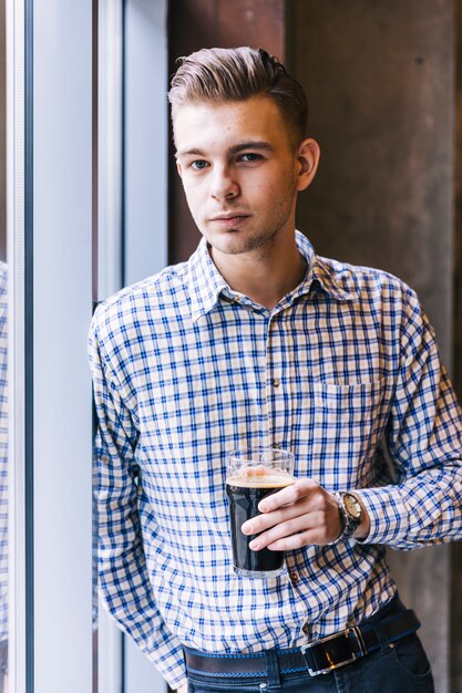 Nahaufnahme eines jungen gutaussehenden Mannes, der die Biergläser betrachten Kamera hält