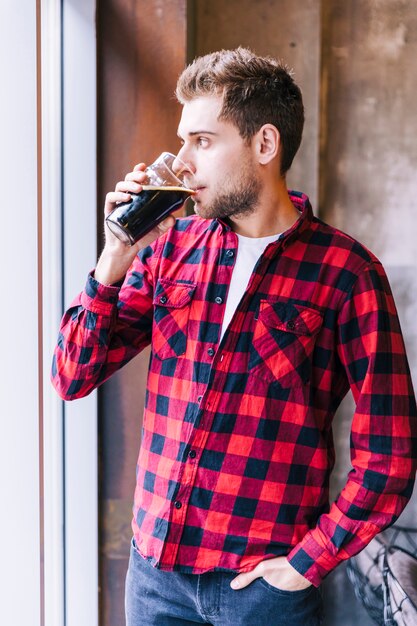 Nahaufnahme eines jungen Mannes mit der Hand in der Tasche die Biergläser trinkend