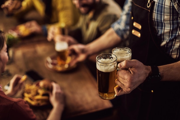 Nahaufnahme eines Kellners, der Bier in einer Bar serviert