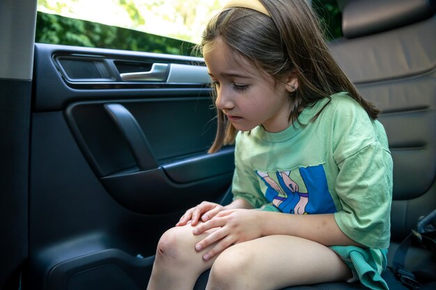 Nahaufnahme eines kleinen Mädchens, das sein geprelltes, verletztes Knie mit den Händen hält