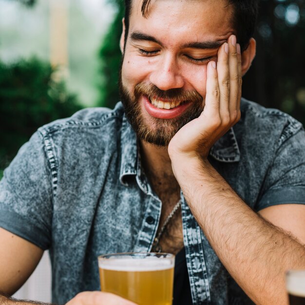 Nahaufnahme eines lächelnden Mannes, der Glas Bier hält