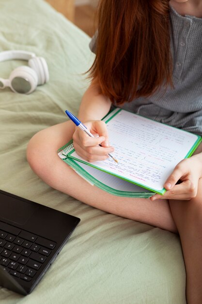 Nahaufnahme eines Mädchens, das sich im Bett Notizen macht