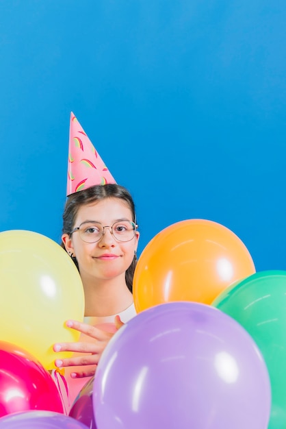 Nahaufnahme eines Mädchens mit bunten Ballonen auf blauem Hintergrund