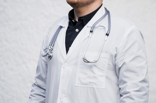 Nahaufnahme eines männlichen Doktors mit Stethoskop um seinen Hals gegen weißen Hintergrund