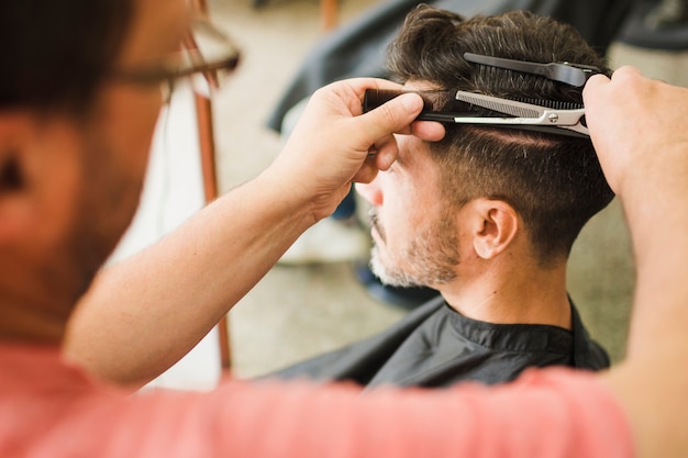 Nahaufnahme eines männlichen Kunden, der Haarschnitt vom Friseur erhält